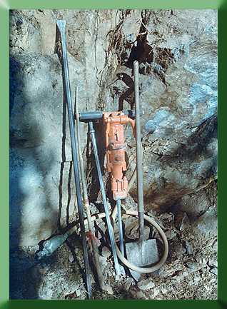Rock drill with tamping stick, rock bar, drill steel and shovel.