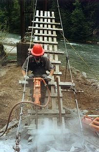 Drilling 14' deep rock anchors from suspended ramp.