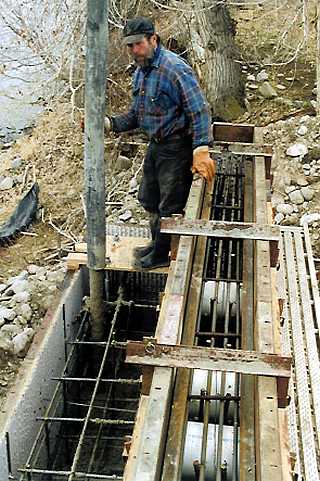 George Tempest guiding concrete pump hose into abutment form.